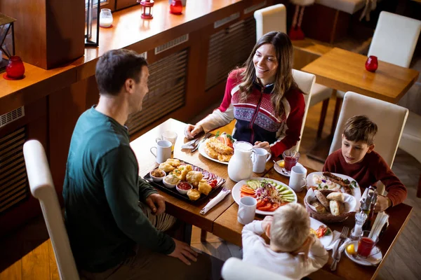 Bir aile kahvaltı etmek için bir restoranda toplanır. Yemek dolu bir masayı paylaşıyorlar. Ebeveynler çocuklarıyla konuşup neşeli bir ortam yaratıyorlar..