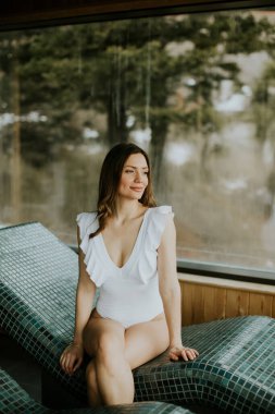 Bir kadın kaplıcada sıcak taştan bir yatakta oturuyor. O, dışarıdaki ağaçlara büyük bir pencereden bakıyor. Doğal ışık içeri girince ortam aydınlanıyor..