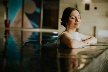 Bir kadın kaplıcadaki su alanından zevk alır. Gözleri kapalı rahatlamış görünüyor. Duvarların rengarenk bir sanatı var ve dekorları çok davetkar. Onun için sessiz bir an..