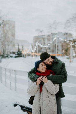 Koreli kadın ve beyaz adam, karlı bir bölgede dururken sarılıyorlar. Kış sahnesindeki ışıklarla çevrili birbirlerine gülümserler. Sıcaklık soğuk ve kar zemini kaplıyor..