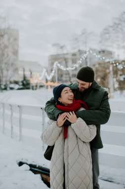 Koreli bir kadın ve Kafkasyalı bir erkek kış ayininde birlikte dururlar. Etrafları karla çevriliyken gülümsüyor ve birbirlerinin arkadaşlığından zevk alıyorlar. Işıklar arka planda görünür..