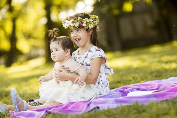 Kleine meisjes zitten op het gras — Stockfoto