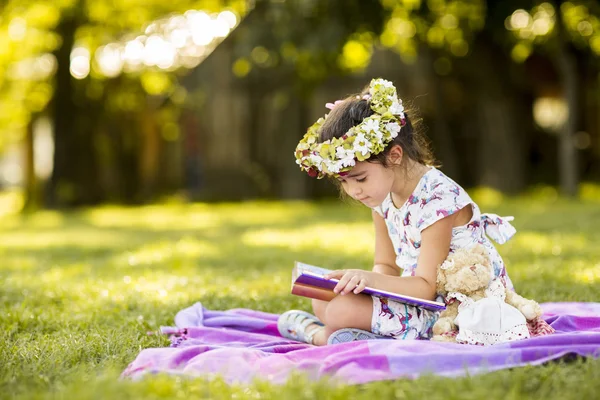 Little girl reading in the park — Stock Photo, Image