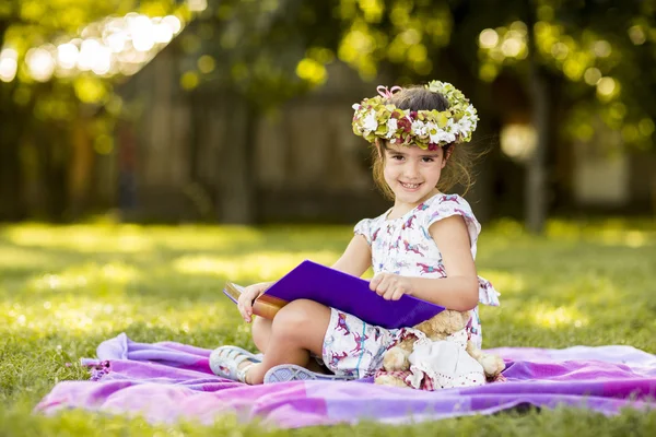 어린 소녀는 공원에서 읽기 — 스톡 사진