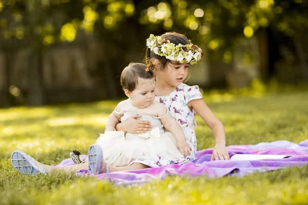 Little girls sitting on the grass — Stock Photo, Image