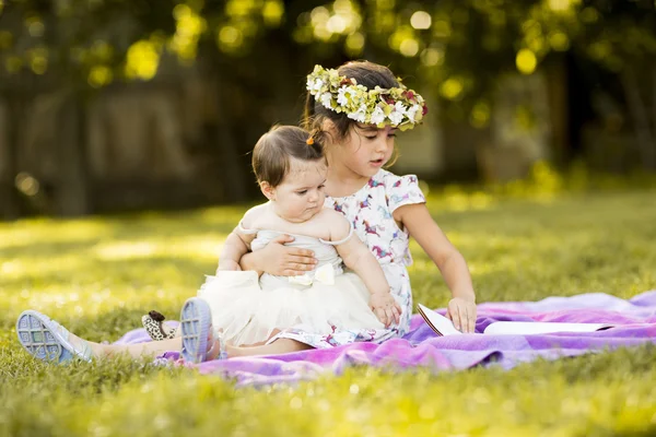 Little girls sitting on the grass — Stock Photo, Image