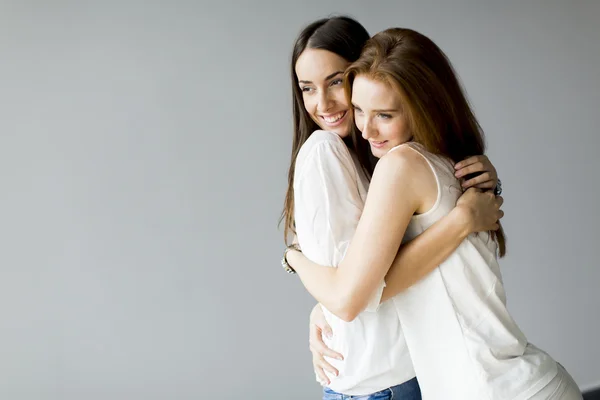 Abbracciare gli amici su sfondo grigio — Foto Stock
