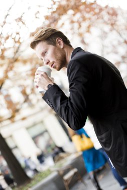 Genç adam kahve içiyor.