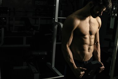 Genç adam spor salonunda antrenman yapıyor.