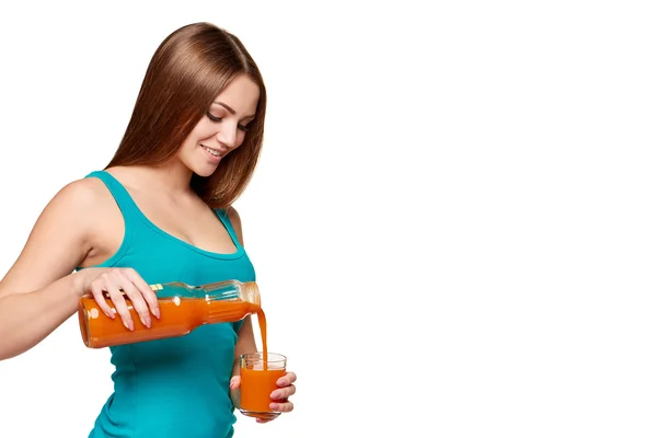 Mujer vertiendo jugo de zanahoria en un vaso — Foto de Stock