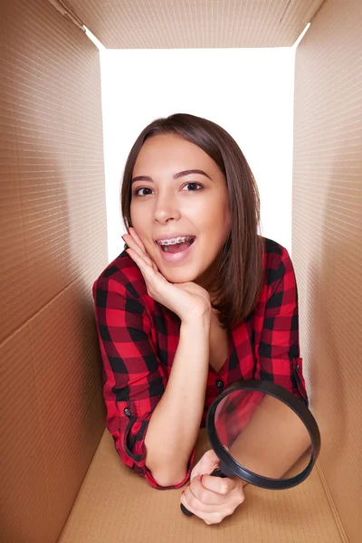 Girl opening a carton box and looking inside — Stock Photo, Image