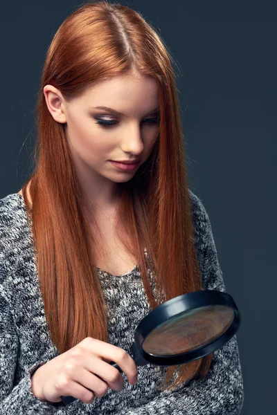 Frau schaut durch Vergrößerungsglas — Stockfoto