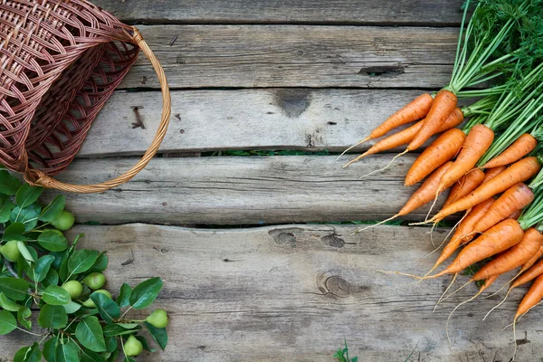 Свіжа морква з пустим кошиком на сільському дерев'яному фоні — стокове фото