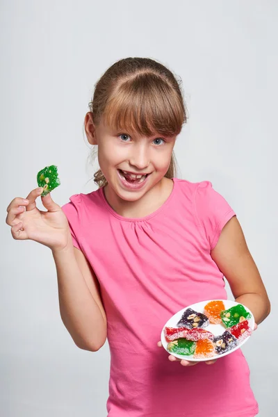 Bir tabak renkli jöle şekerler ile tutarak mutlu küçük kız — Stok fotoğraf
