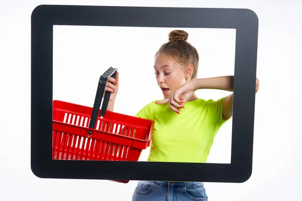 网上购物的概念 时髦的少女拿着空购物篮从数字屏幕上看过去 惊讶地看着它 被淡淡的背景隔开了 — 图库照片