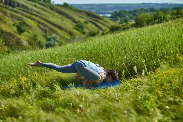 若いです女性ありますヨガで緑の夏の牧草地 — ストック写真