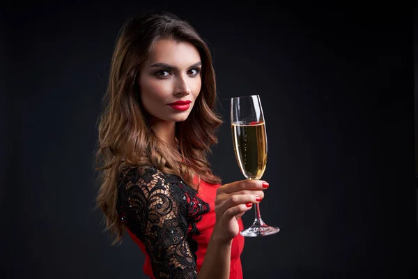 假期和庆祝的概念 在深色背景下 穿着红色衣服 拿着一杯香槟看着相机的漂亮女人的衣服 — 图库照片