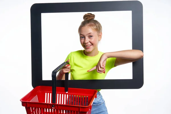 Online-Einkaufskonzept. Trendiges Teenie-Mädchen mit leerem Warenkorb — Stockfoto