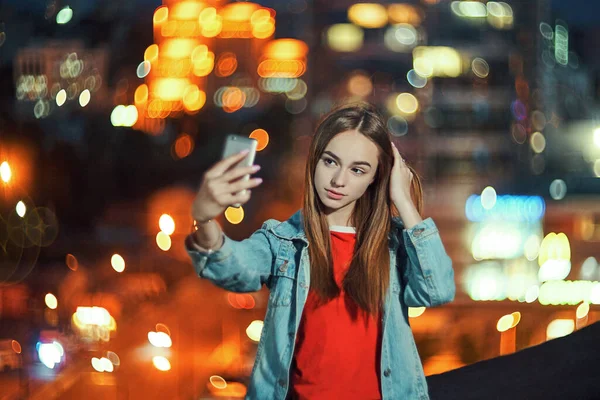Девушка-подросток на фоне городского пейзажа делает автопортрет со своим смартфоном — стоковое фото