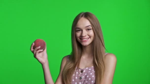 Glimlachend meisje dragen zomer jurk glimlachen en het houden van een perzik — Stockvideo