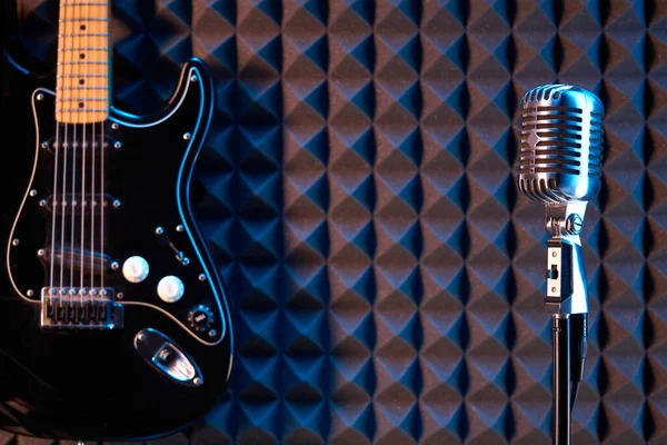 工作室冷凝器麦克风和黑色电吉他 在声学泡沫面板背景上 — 图库照片