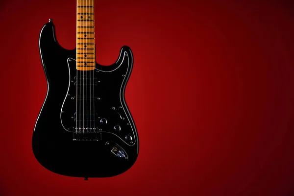 Black electric guitar on red background — Stock Photo, Image