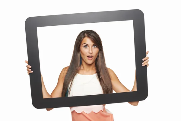 Возбужденная женщина смотрит через планшетную рамку — стоковое фото
