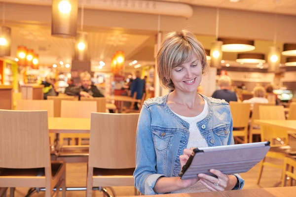 Женщина, сидящая в кафе с цифровым планшетом — стоковое фото