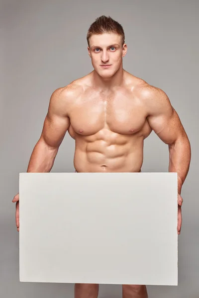 Muscular man holding white banner with copy space — 图库照片