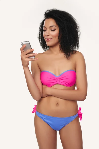 Улыбающаяся женщина в купальнике с мобильным телефоном — стоковое фото