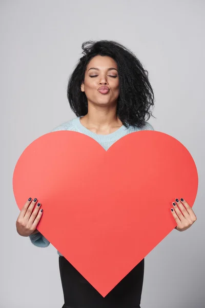 Chica sosteniendo gran forma de corazón rojo — Foto de Stock