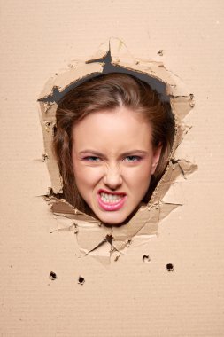Displeased girl peeping through hole in paper clipart