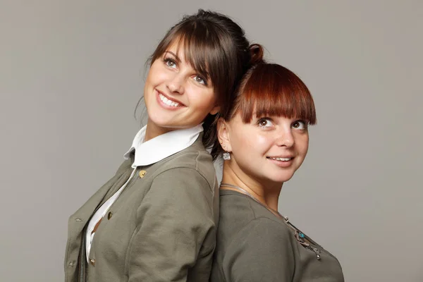 Closeup of two smiling girls standing back to back looking upwards — Stock Photo, Image