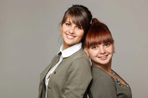 Closeup of two smiling girls standing back to back — Stock Photo, Image