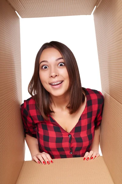 Girl opening a carton box and looking inside — Stock Photo, Image