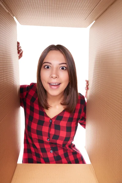 Girl opening a carton box and looking inside — Stock Photo, Image