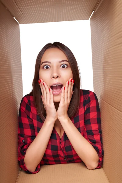 Girl opening a carton box and looking inside — Stock Photo, Image