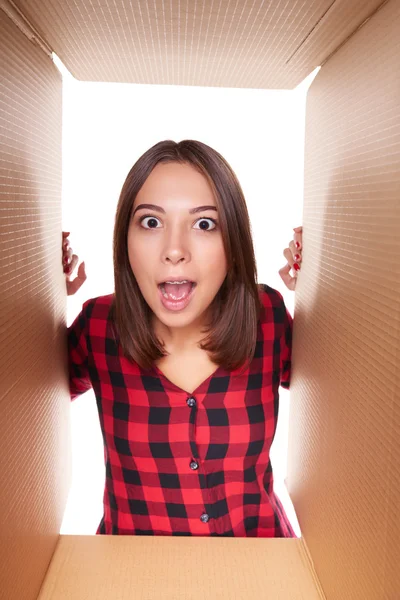 Girl opening a carton box and looking inside — Stock Photo, Image