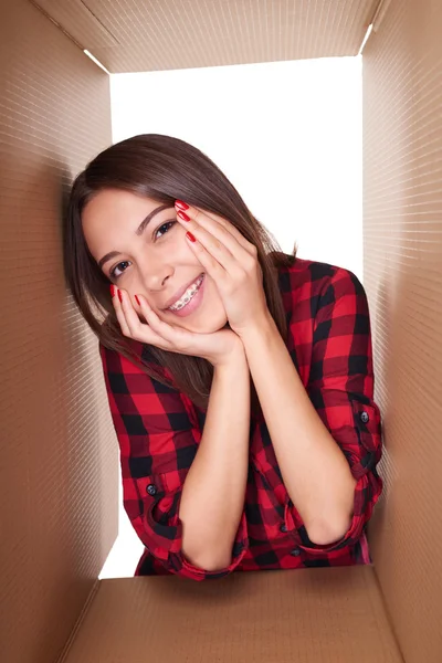 Girl opening a carton box and looking inside — Stock Photo, Image