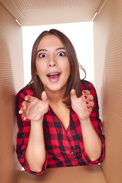 Girl opening a carton box and looking inside — Stock Photo, Image