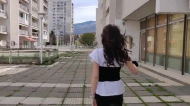 Moda kıyafetiyle sokakta poz veren genç bir kadın.