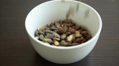 Tuzlu balkabağı tohumları küçük beyaz kaseye dökülüyor.