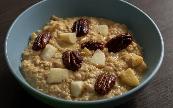 Taze elma dilimleri ve karamelli cevizlerle kaplı kremalı balkabağı yulaf ezmesi.