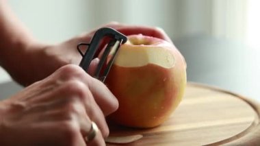 Kadın elleri taze elmayı soyuyor. Yakın plan.