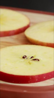 Kırmızı elmayı dilimleyip yuvarlak daireler çiziyor.