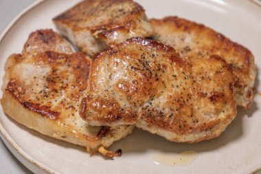 Beyaz tabakta servis edilen lezzetli domuz pirzolası.