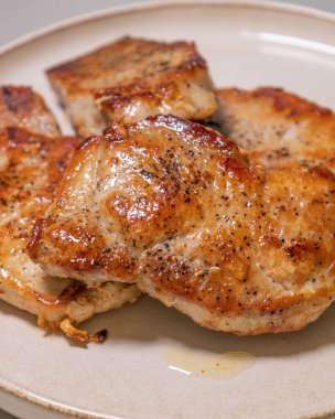 Beyaz bir tabakta servis edilen leziz domuz pirzolası.