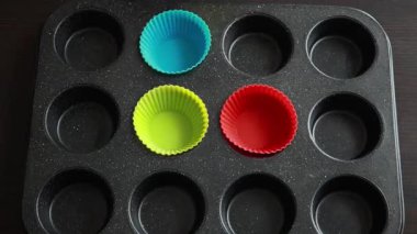 Eller silikon kek bardaklarını pişirme tepsisine yerleştiriyor.