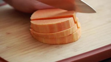 Kesme tahtasında kabakları küp küp doğrayan eller.