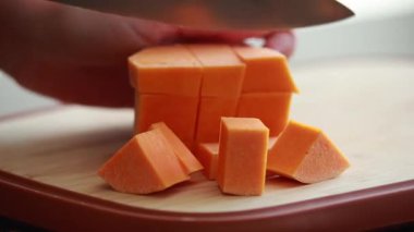 Kesme tahtasında kabakları küp küp doğrayan eller.